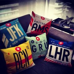 four pillows are sitting on a couch in front of a window, with the letters j & m and gru printed on them