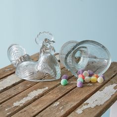 a glass chicken sitting on top of a wooden table next to some candy candies