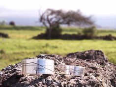 two silver bracelets sitting on top of a rock in the middle of a field