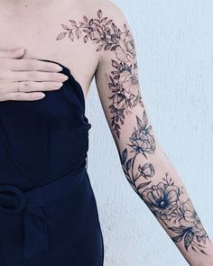 a woman wearing a black dress with flowers on her arm