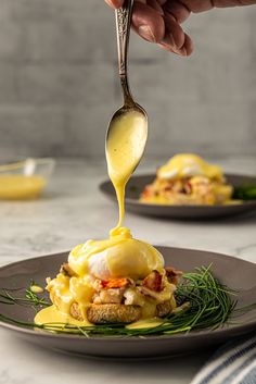 a spoon drizzling sauce onto an open faced sandwich on a black plate