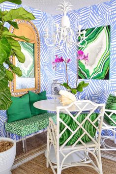 a dining room with blue and green wallpaper, white wicker chairs and a round table