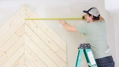 a man is measuring the height of a wooden wall with a tape measure on it