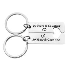 two silver key chains with the words 20 years and counting on them are shown in front of a white background