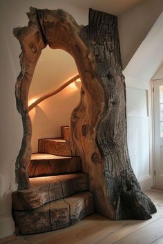 a tree trunk is in the middle of a room with stairs leading up to it