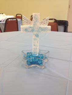 a glass bowl filled with blue beads and a cross on top of it, sitting on a table