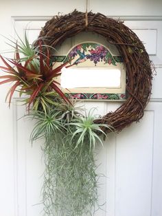 a wreath with air plants hanging from it's side next to a white door