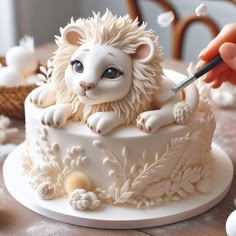 someone is decorating a cake with white frosting and a lion figurine