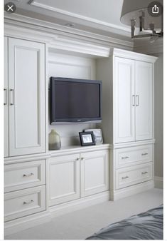 a flat screen tv mounted to the side of a white cabinet in a room with carpeted flooring