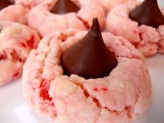 several pink cookies with chocolate on top are sitting on a white plate, ready to be eaten