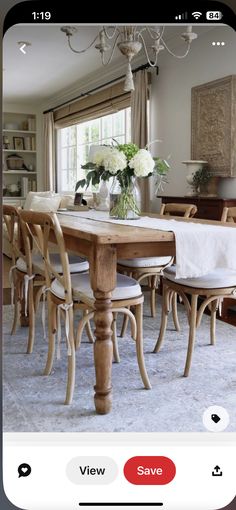 a dining room table with chairs and a vase filled with flowers on top of it