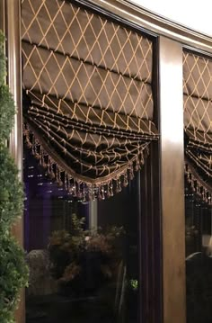 a window covered in brown curtains next to a potted plant