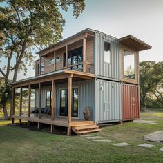 a house made out of shipping containers in the middle of a grassy area with steps leading up to it