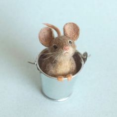 a tiny mouse sitting in a small metal cup