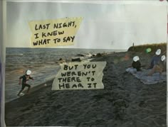 a group of people sitting on top of a beach next to the ocean with signs