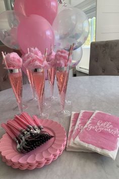 a table topped with pink desserts and balloons