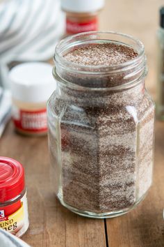 a jar filled with brown sugar sitting on top of a wooden table next to other spices