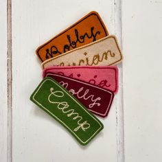 four different colored name tags sitting on top of a white door frame with the word goodbye written in cursive writing