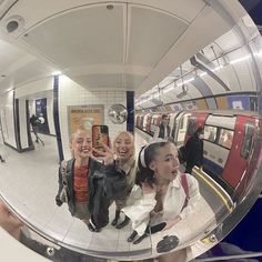 two women taking a selfie in a mirror at a subway station with their cell phone