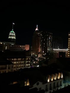 the city is lit up at night with lights on and buildings in the foreground