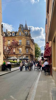 people are walking down the street in an old european town with tall buildings on either side