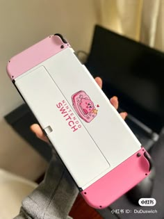 a person holding up a pink and white nintendo wii game console case in their hands