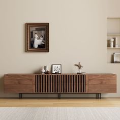 a living room with a large wooden cabinet and pictures on the wall above it, in front of a white rug