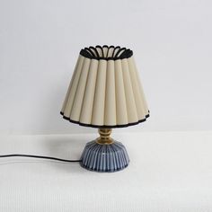 a lamp that is sitting on top of a white surface with a black cord attached to it