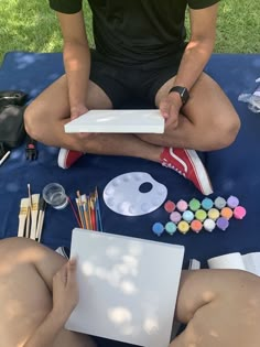 two people sitting on the ground with art supplies