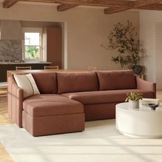 a living room with a sectional couch and coffee table in the corner, next to a large potted plant