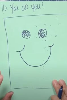 someone is drawing a smiley face on a piece of paper