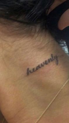 the back of a woman's neck with her name tattooed on it, in cursive writing