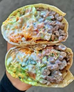 two tacos filled with meat, cheese and other toppings on a person's hand