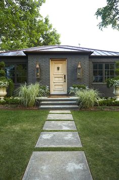 a house with steps leading up to the front door and grass in front of it