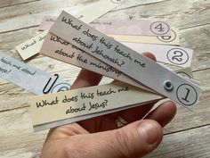 someone is holding four bookmarks with some writing on them and one has a question mark