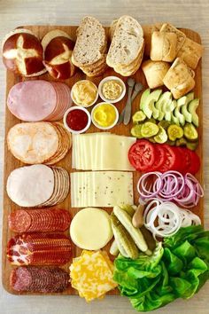 an assortment of meats and cheeses on a cutting board with lettuce