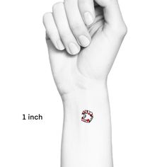 a hand with a red and white heart tattoo on it's left wrist is shown