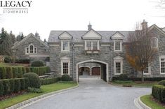 a large stone house surrounded by hedges and trees