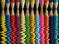 many different colored pencils are lined up in the same row and reflected in the water