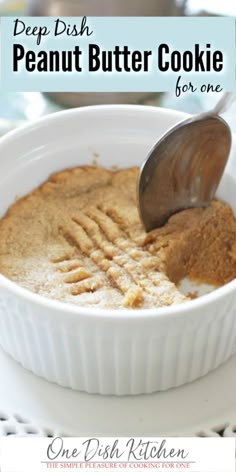 a white bowl filled with peanut butter cookie batter on top of a plate next to a spoon