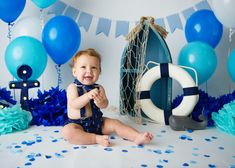 a baby sitting on the floor in front of blue and white decorations