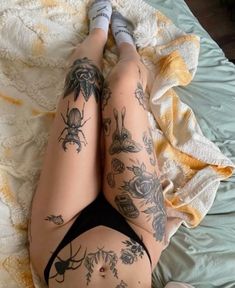 a woman laying on top of a bed with tattoos on her legs and stomachs