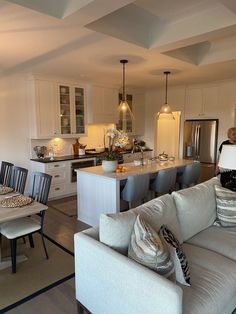 a living room filled with furniture next to a kitchen and dining room table in front of an island