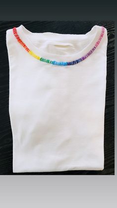 a white t - shirt with multi colored beads on it