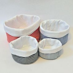 four baskets are lined up on a white surface with red and black checkered fabric