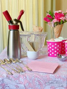 a table topped with pink cups and silverware