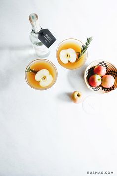 two glasses filled with liquid and apples