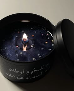 a candle in a black container with stars on it