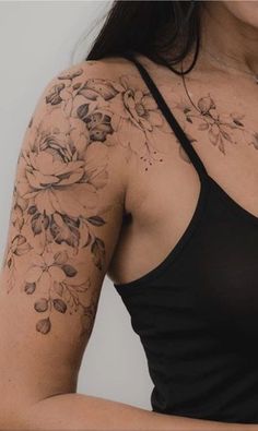 a woman wearing a black tank top with flowers on her arm and chest tattoo design