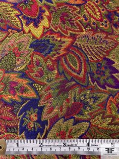 a ruler is next to a colorful paisley print fabric with flowers and leaves on it